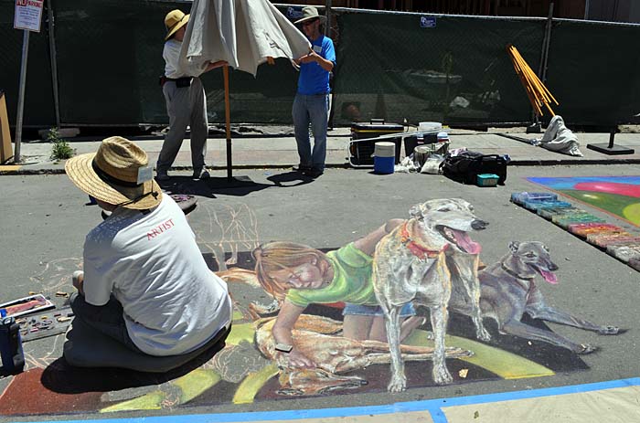 Cheryl and Darin erect an umbrella while Wayne paints